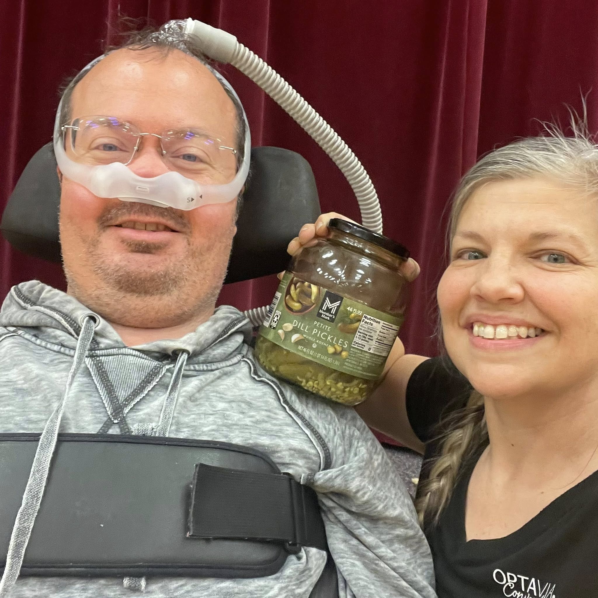 Ryan and Angela smiling with a jar of pickles