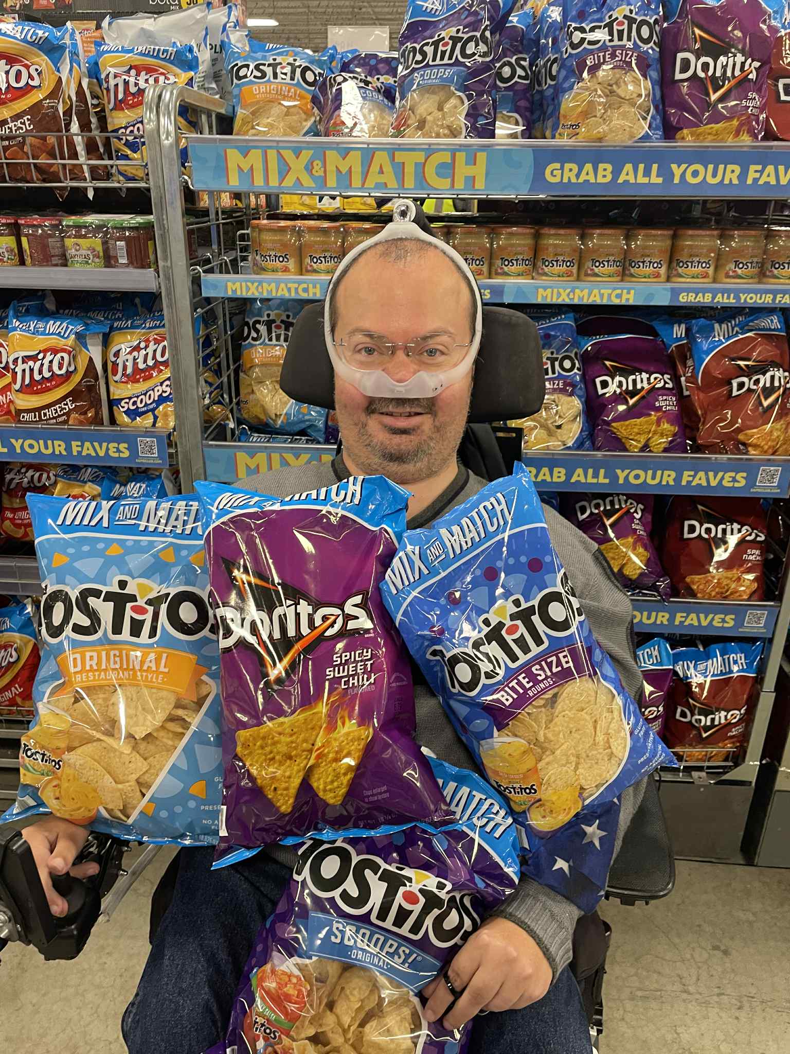 Ryan holding several large bags of chips in a grocery aisle